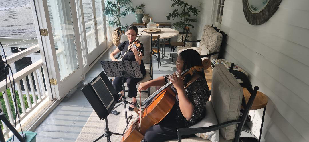 Lumina violin and cello duo performing on a porch at Primrose Cottage, Roswell