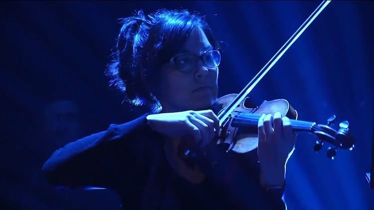 Rosie Riquelme Antunez performing violin on stage during a Trans-Siberian Orchestra concert.